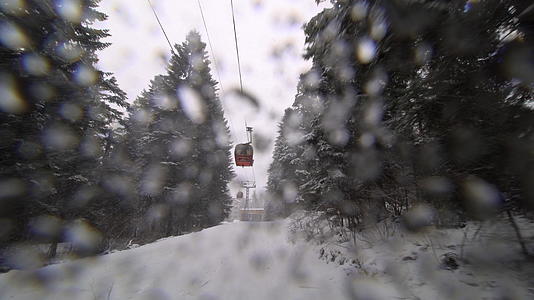 下雪时小木屋在滑雪中心升起冬天移动到冬天Gondolas视频的预览图
