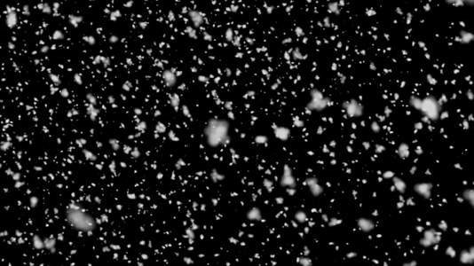 黑色背景下从顶部掉落的大片雪碎片hd视频的预览图