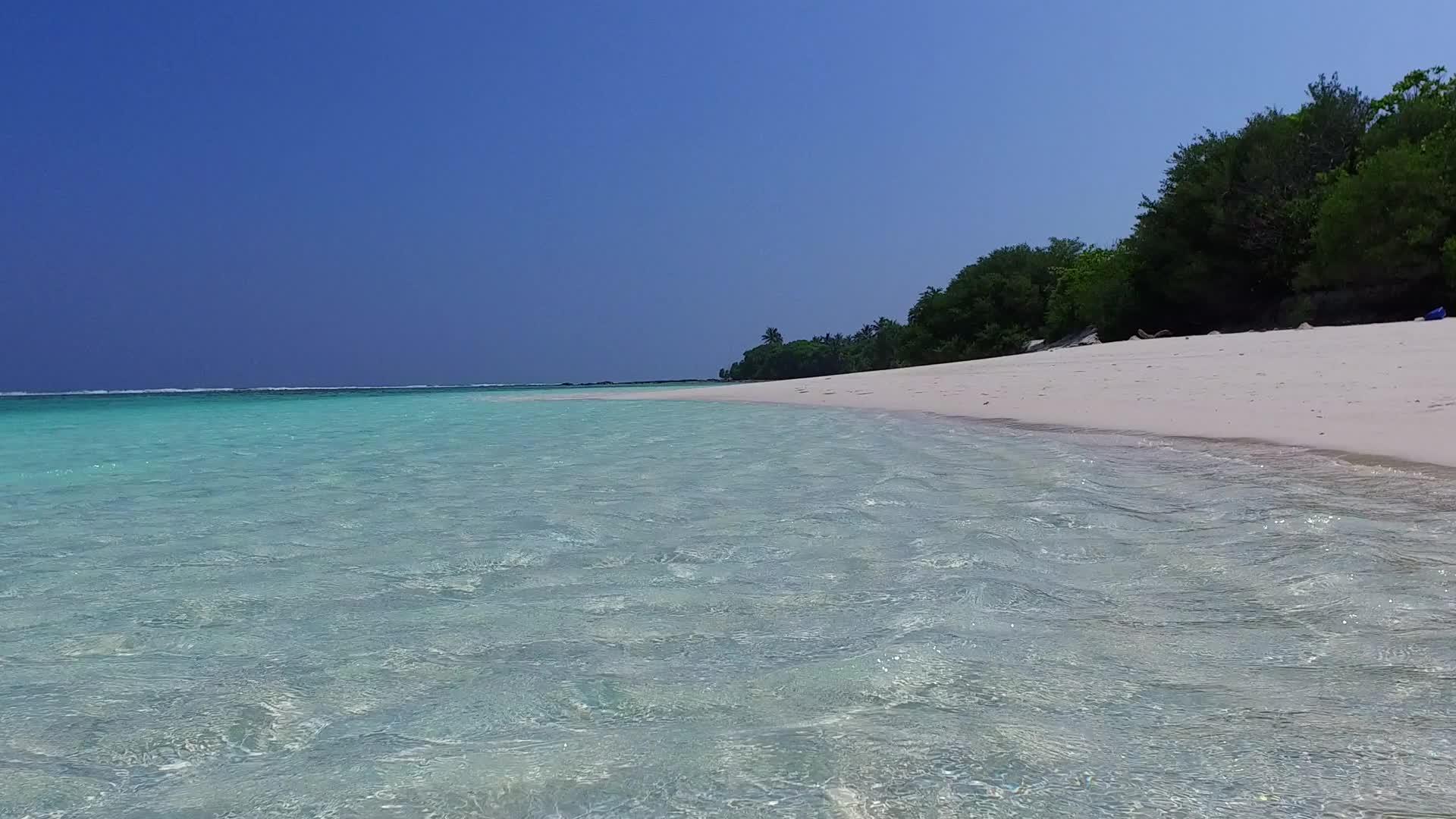 蓝色的绿色海洋和安静的海岸线在阳光下的白色海滩背景下视频的预览图