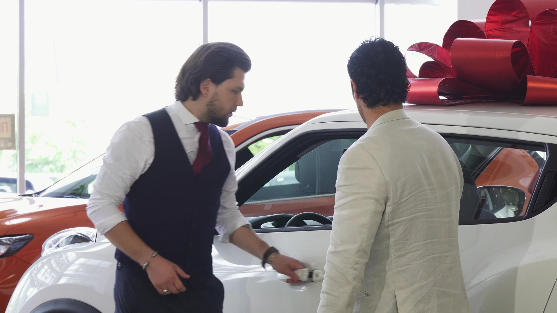 专业的汽车推销员为他的男性顾客开门视频的预览图