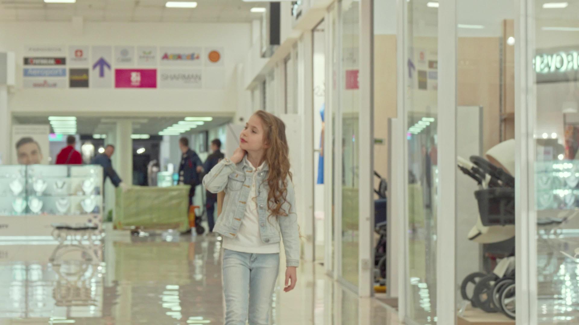 可爱的小女孩带着购物袋在商场散步视频的预览图