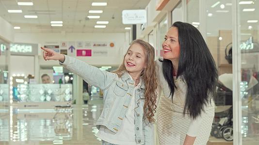 这个可爱的卷发女孩和她的母亲在商场里购物视频的预览图