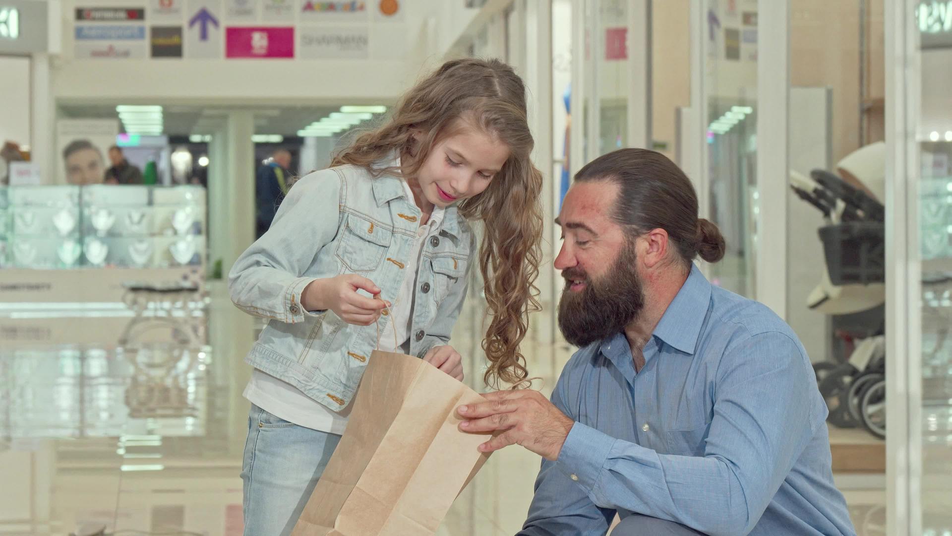 可爱的小女孩和她的父亲看着商场里的购物袋看着她的父亲视频的预览图