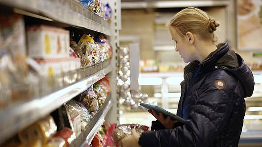 女性在超市购买食品并检查她们的触摸板清单视频的预览图