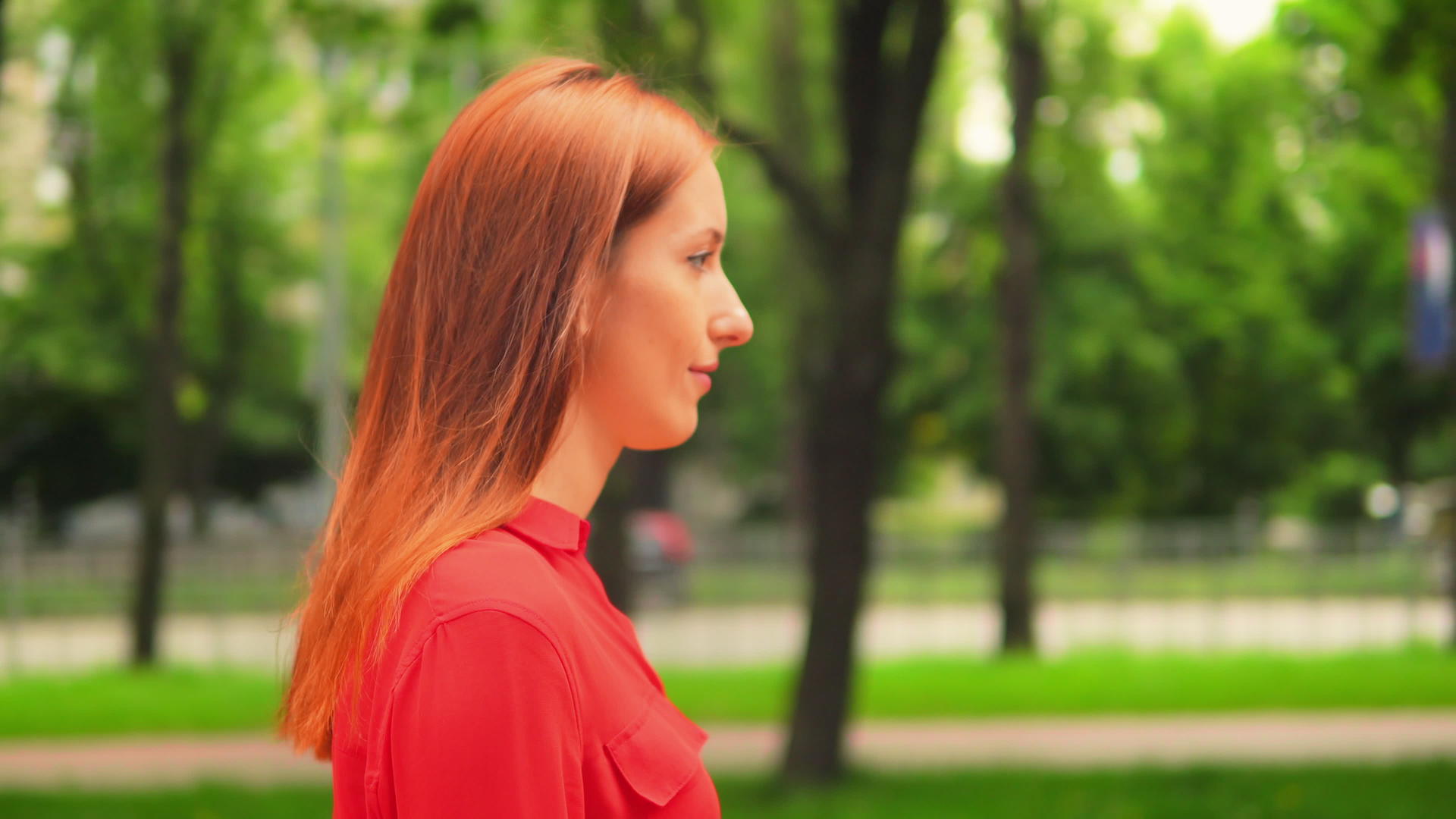 红发女孩在绿色公园散步视频的预览图