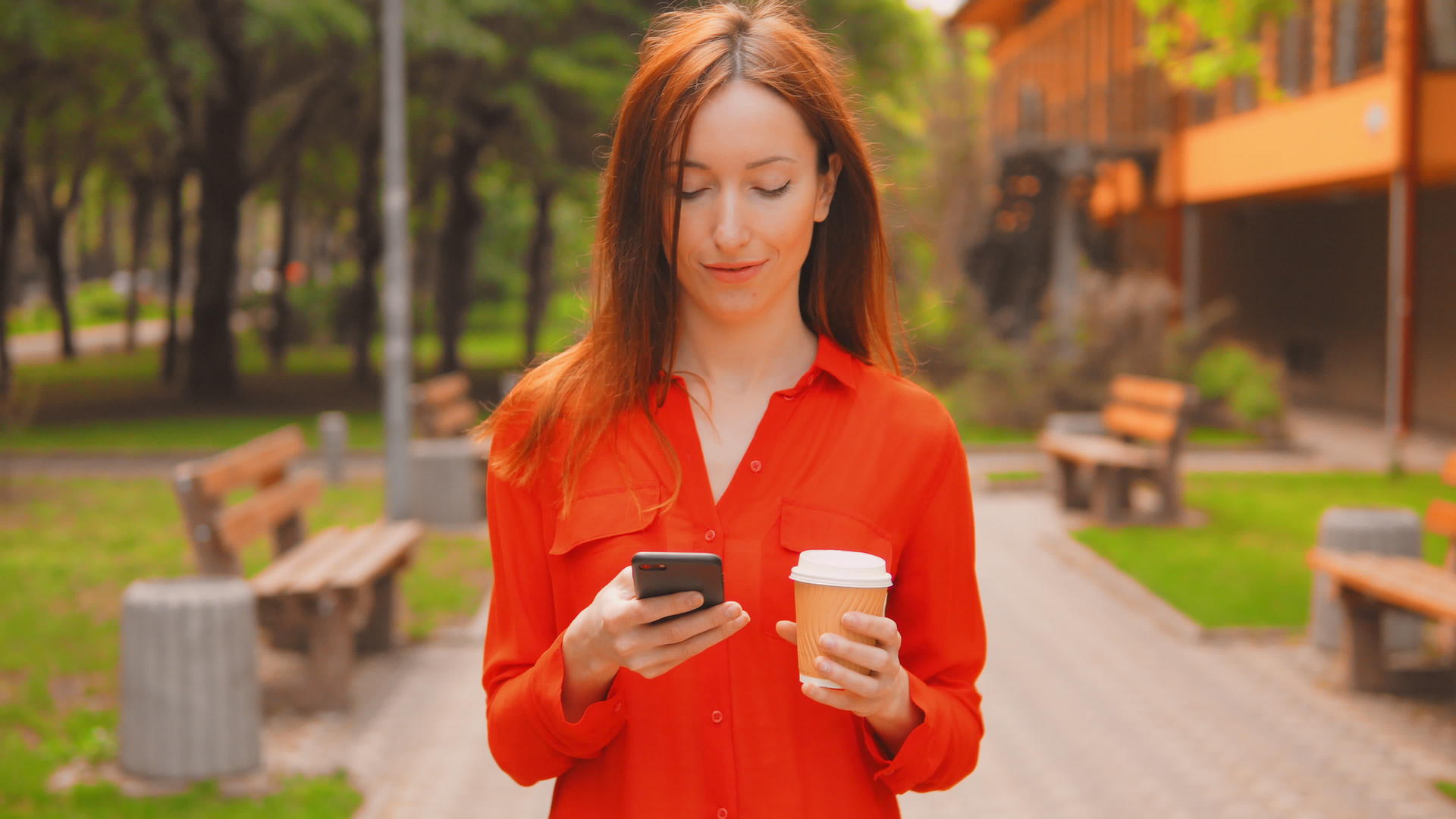 在绿色公园发短信的红发女性视频的预览图