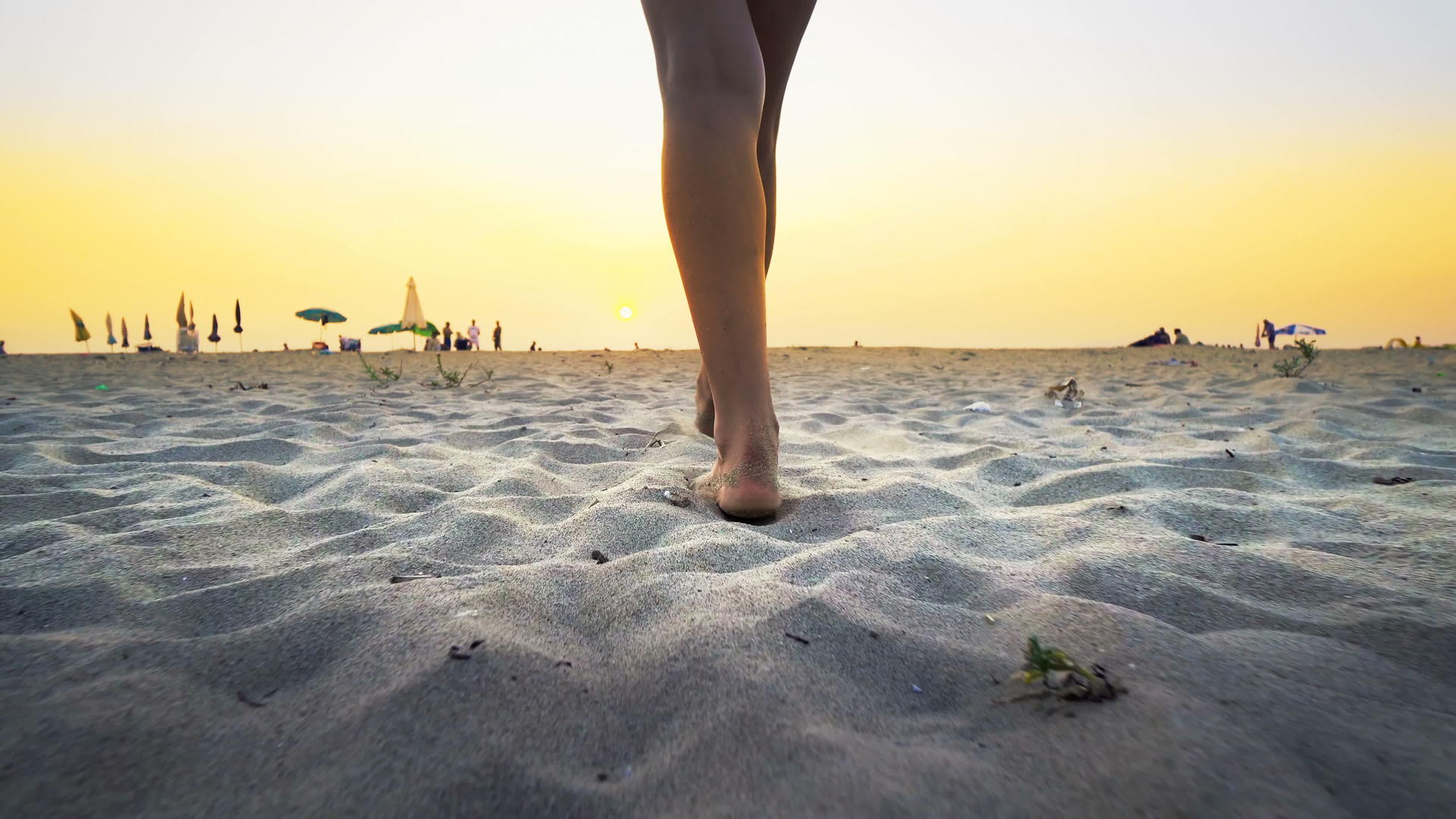 日落时游客赤脚在海滩上行走视频的预览图