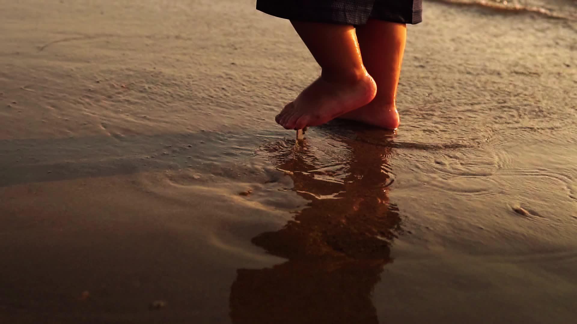 在海滩上散步的婴儿和母亲从夕阳和波浪中慢慢地移动视频的预览图