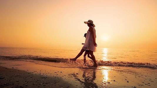 日落时走在海边空荡荡的沙滩上快乐的家庭慢动作视频的预览图
