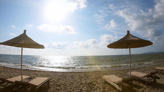 日出时第一个视角是海滩度假胜地和热带岛屿上的草伞和休息者视频的预览图
