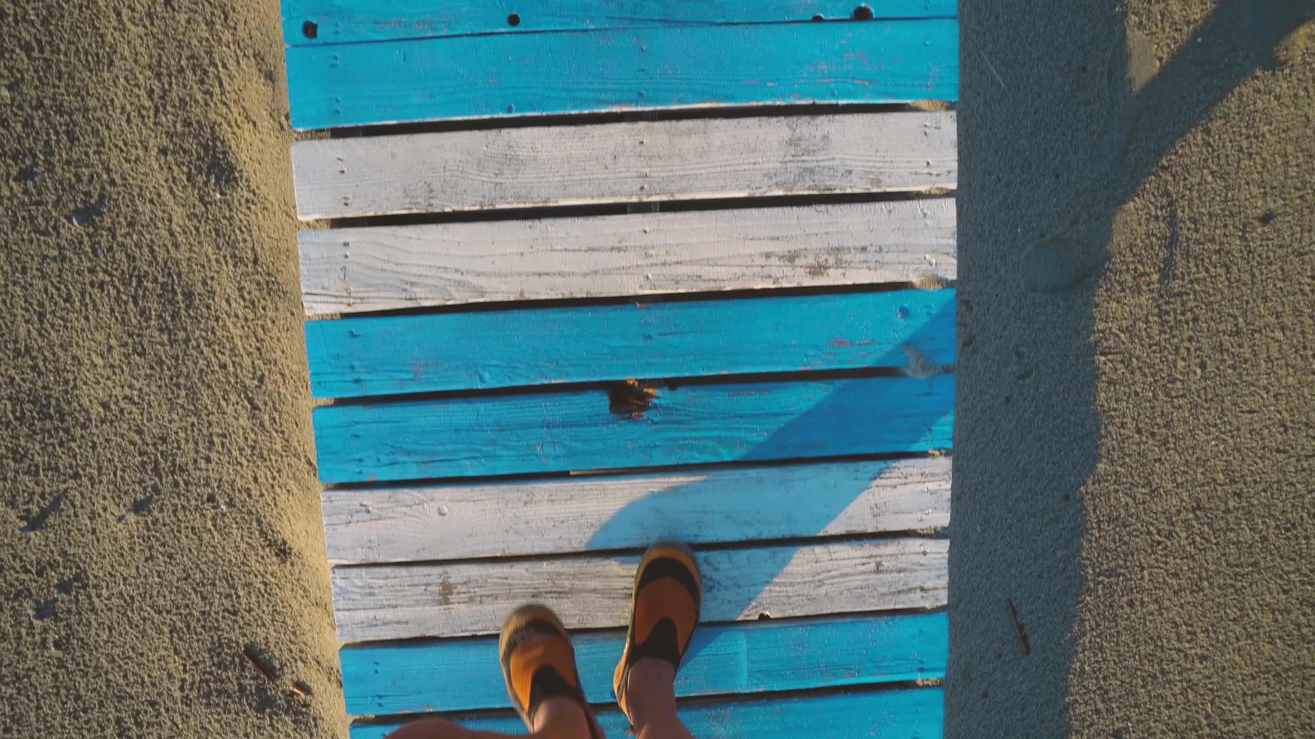 坐在橙色运动鞋上抬头看着脚的第一个视角走在被沙子覆盖的地方视频的预览图