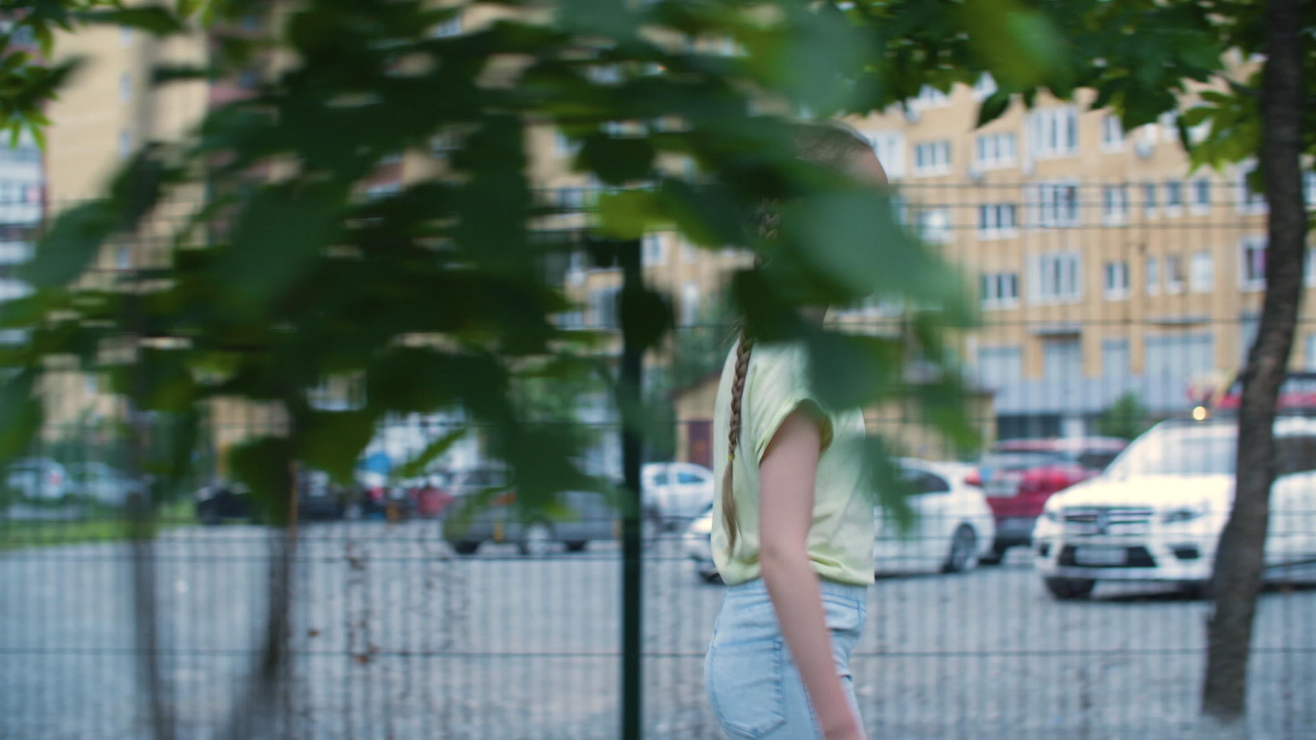 走在现代城市住宅区的两条辫子的年轻女孩视频的预览图