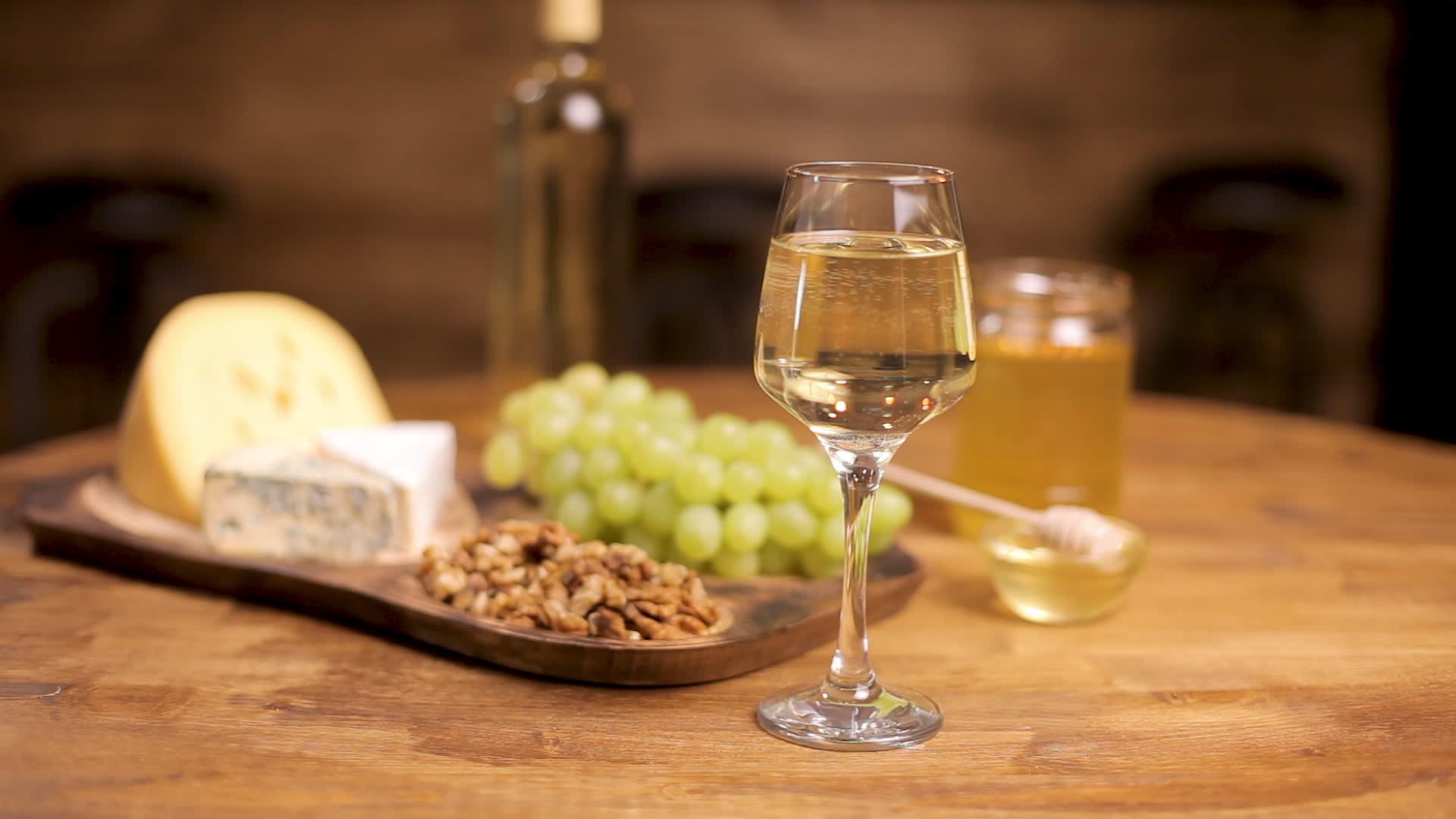 在木桌上放一杯白葡萄酒配上奶酪和葡萄视频的预览图