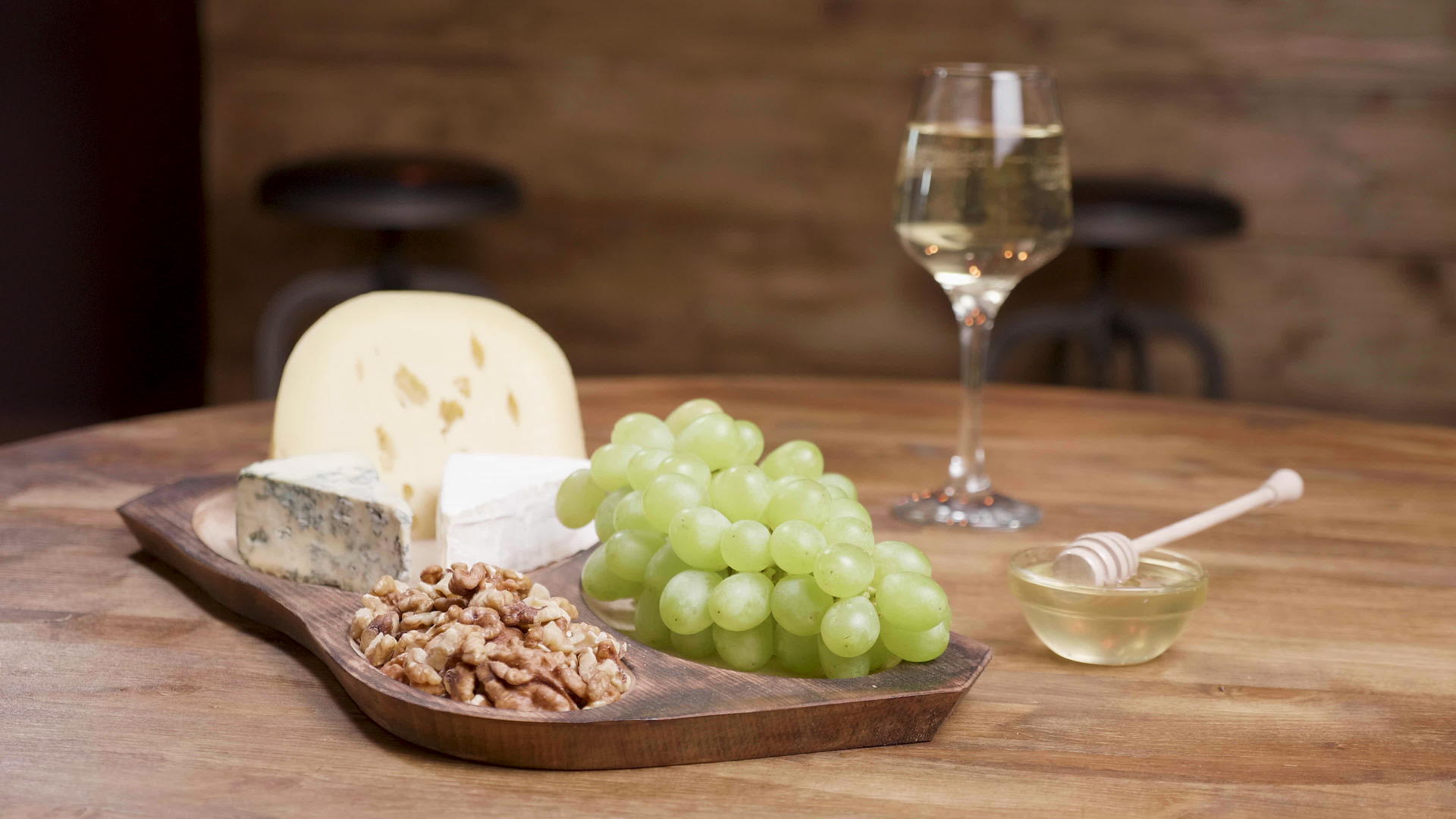 木桌上有蜂蜜、核桃和葡萄酒的奶酪和葡萄视频的预览图