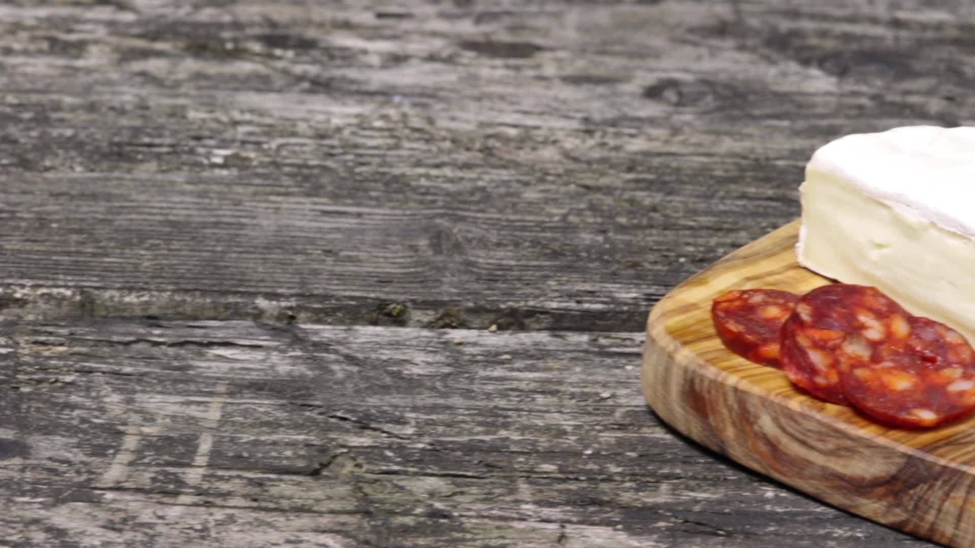 香肠、西红柿、大蒜泡沫和木桌旁的小奶酪视频的预览图