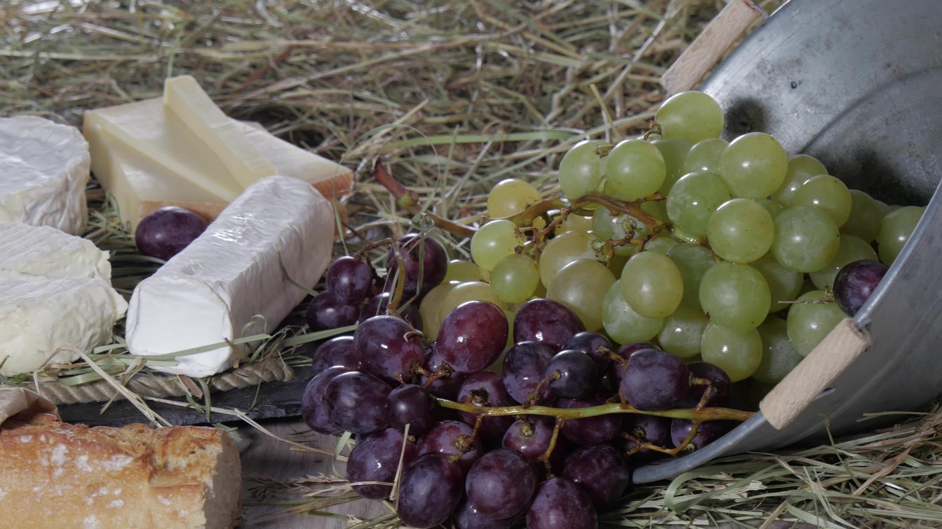 稻草上有一堆法国奶酪、红葡萄和白葡萄视频的预览图