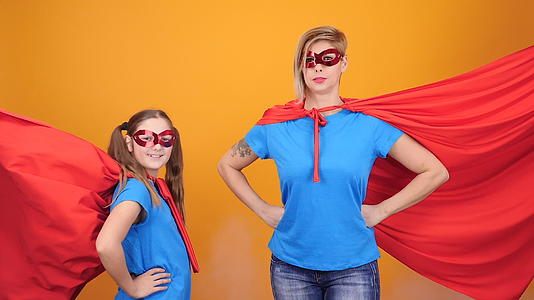 快乐的年轻女孩和带有超级超级英雄斗篷和面具的母亲视频的预览图