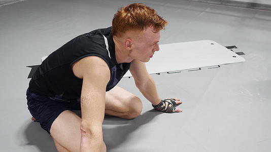 在搏击俱乐部进行战斗训练后跆拳道男子坐在地板上休息视频的预览图
