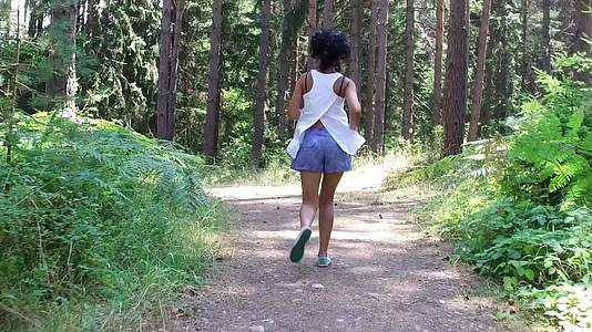年轻美女在森林里慢慢地慢跑向后看射击视频的预览图