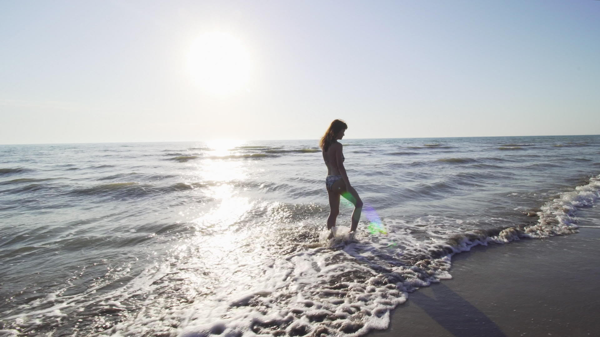 穿着比基尼的女孩在海上玩得很开心日落时泼水在海滩上泼水视频的预览图