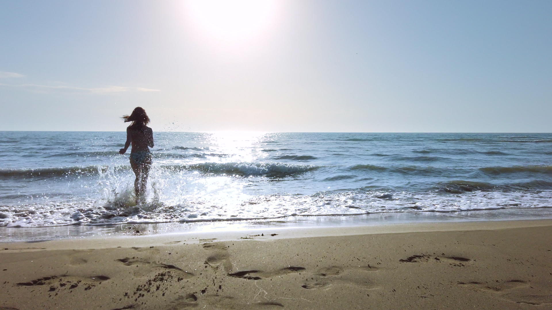 穿着比基尼的漂亮女孩在海上快乐地玩耍日落时微笑和泼水视频的预览图
