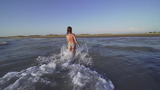 日落时穿着比基尼的女孩在海里跑来跑去视频的预览图