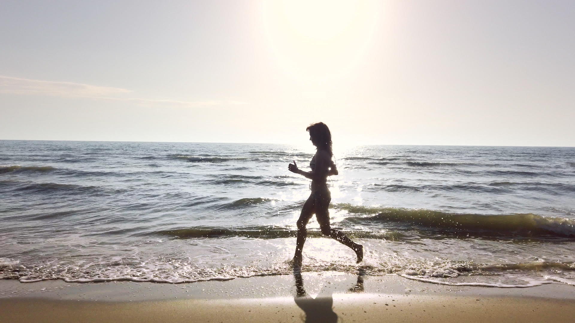快乐美丽的双影女孩穿着比基尼日落时在海滩上奔跑视频的预览图