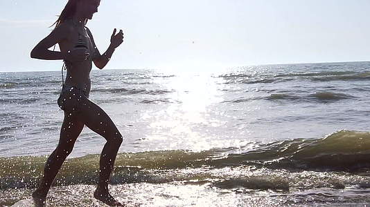 快乐的双影女孩穿着比基尼日落时在海滩上泼水视频的预览图