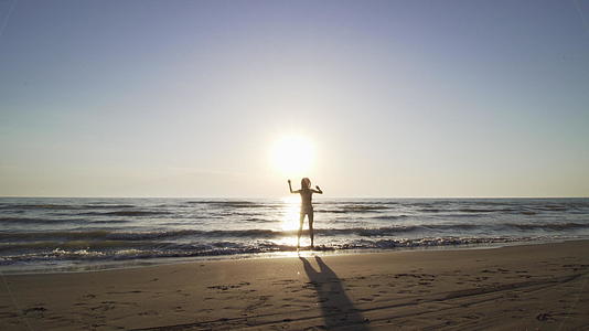 日落时穿着比基尼的月光女孩在海滩上快乐地跳舞视频的预览图