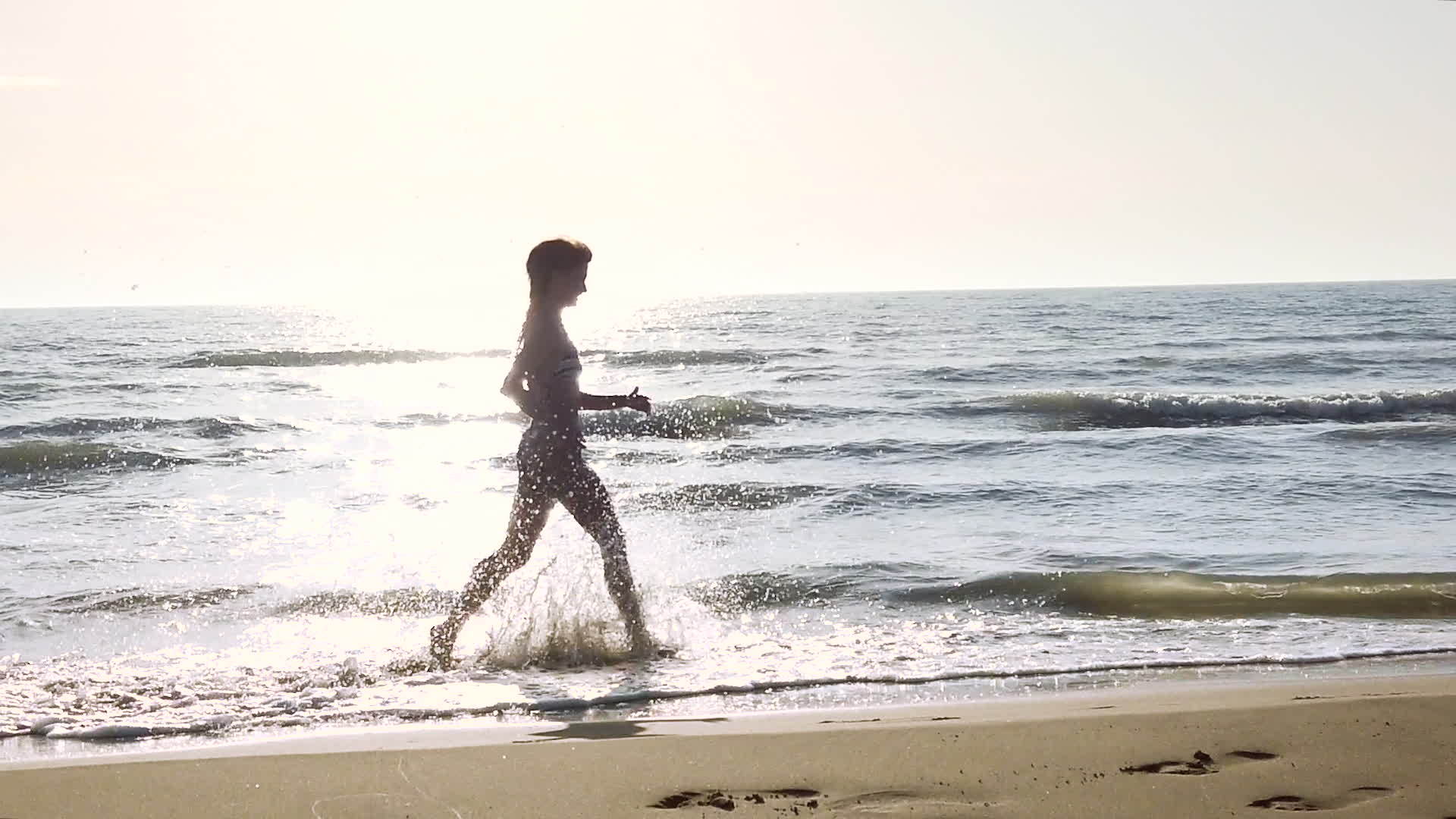 快乐的双影女孩穿着比基尼日落时在海滩上泼水视频的预览图