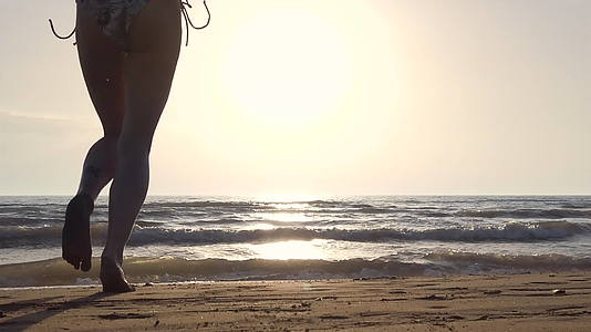 月光女孩在日落时穿着比基尼在海滩上从水中跳下来视频的预览图
