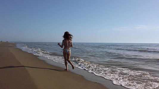 比基尼女孩在日落时在海滩上慢慢泼水视频的预览图