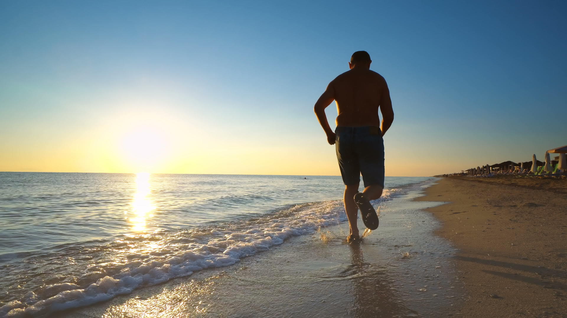 一个年轻人在令人惊叹的日落中在海跑视频的预览图
