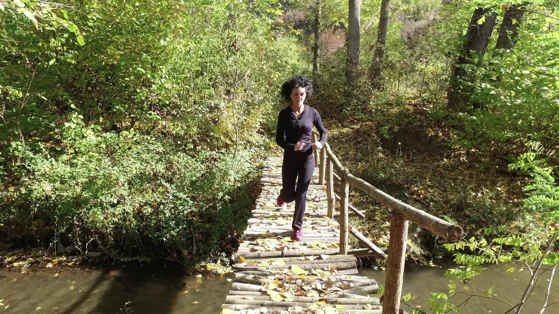 美丽的年轻女模特女子在木桥上的森林公园里训练跑来跑去视频的预览图