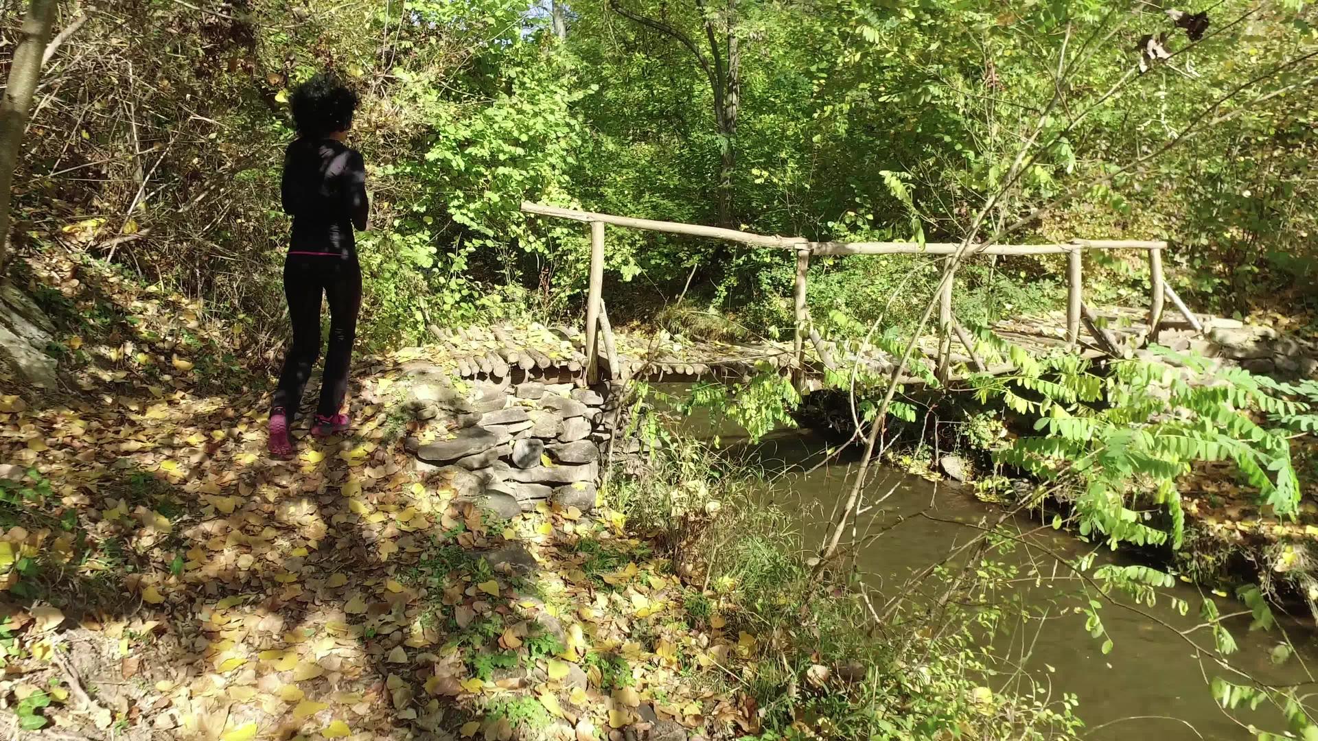 这位运动女子在森林小路上慢跑穿过木桥追踪射击视频的预览图