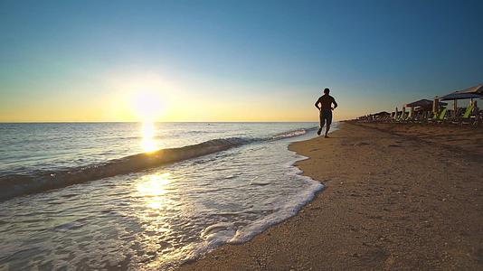 男子在阳光明媚的海滩上奔跑视频的预览图