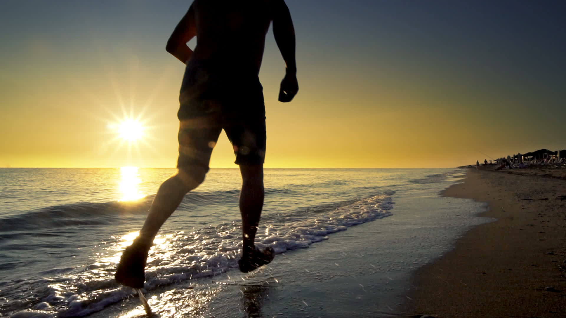 男人在沙滩上跑在阳光下慢慢地跑视频的预览图