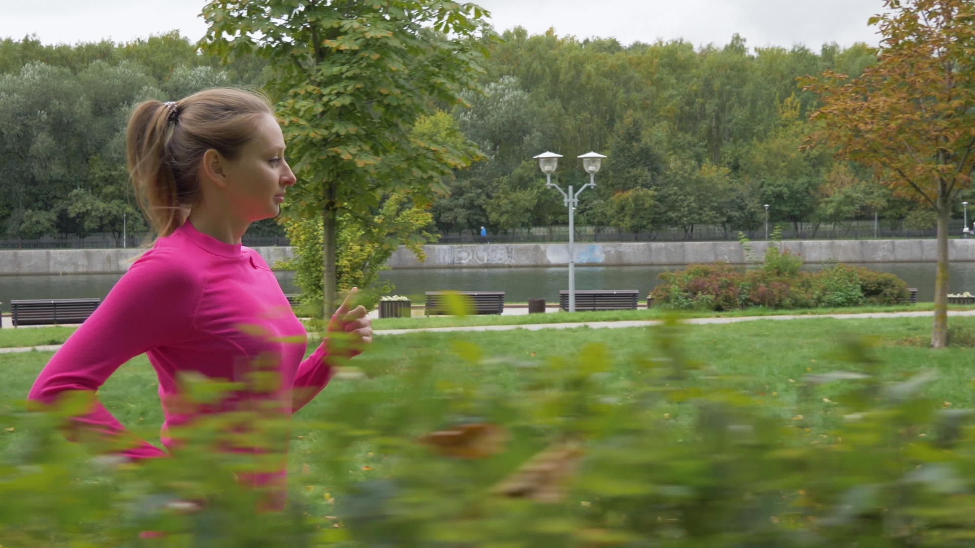 年轻的caucasian女人在绿色公园的灌木丛中奔跑视频的预览图