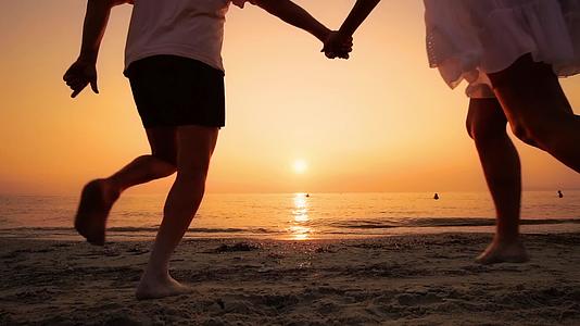在海滩上奔跑的情侣们在海边的太阳结束时手牵着手慢慢地跳了起来视频的预览图