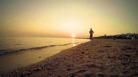 孤独的运动员在空旷的海边慢跑与日落相反视频的预览图