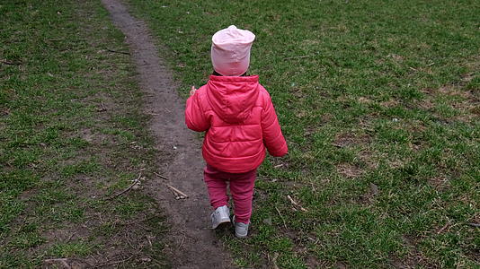 摄像机跟着一个小女孩在春草上行走然后视线视频的预览图