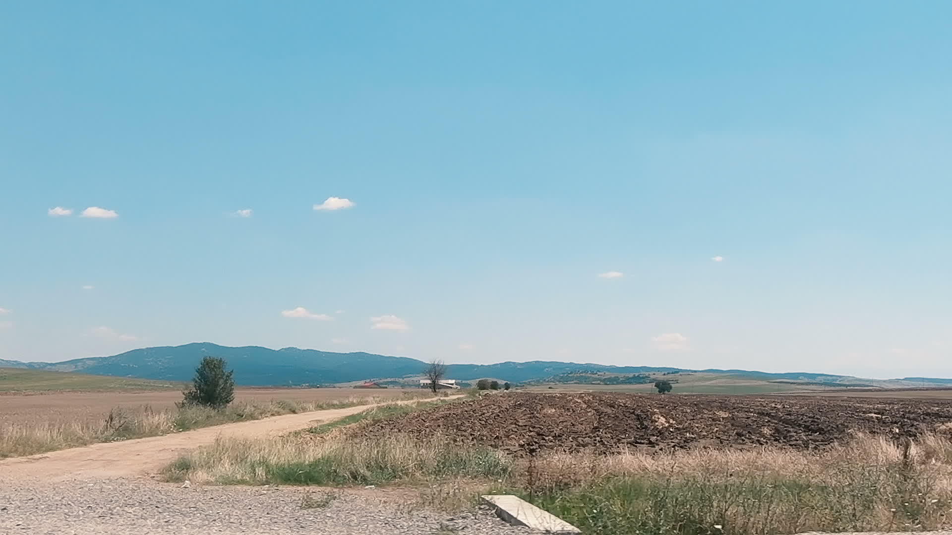 在田地和草原旁的乡村道路上行驶视频的预览图