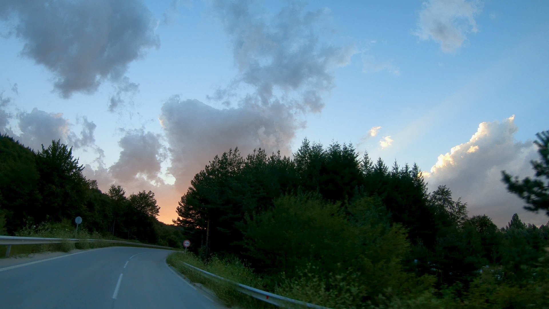 日落时开车在蜿蜒的山路上视频的预览图