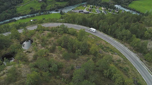 秋天白色房车在挪威的乡间小路上行驶树木和城市鸟瞰图视频的预览图