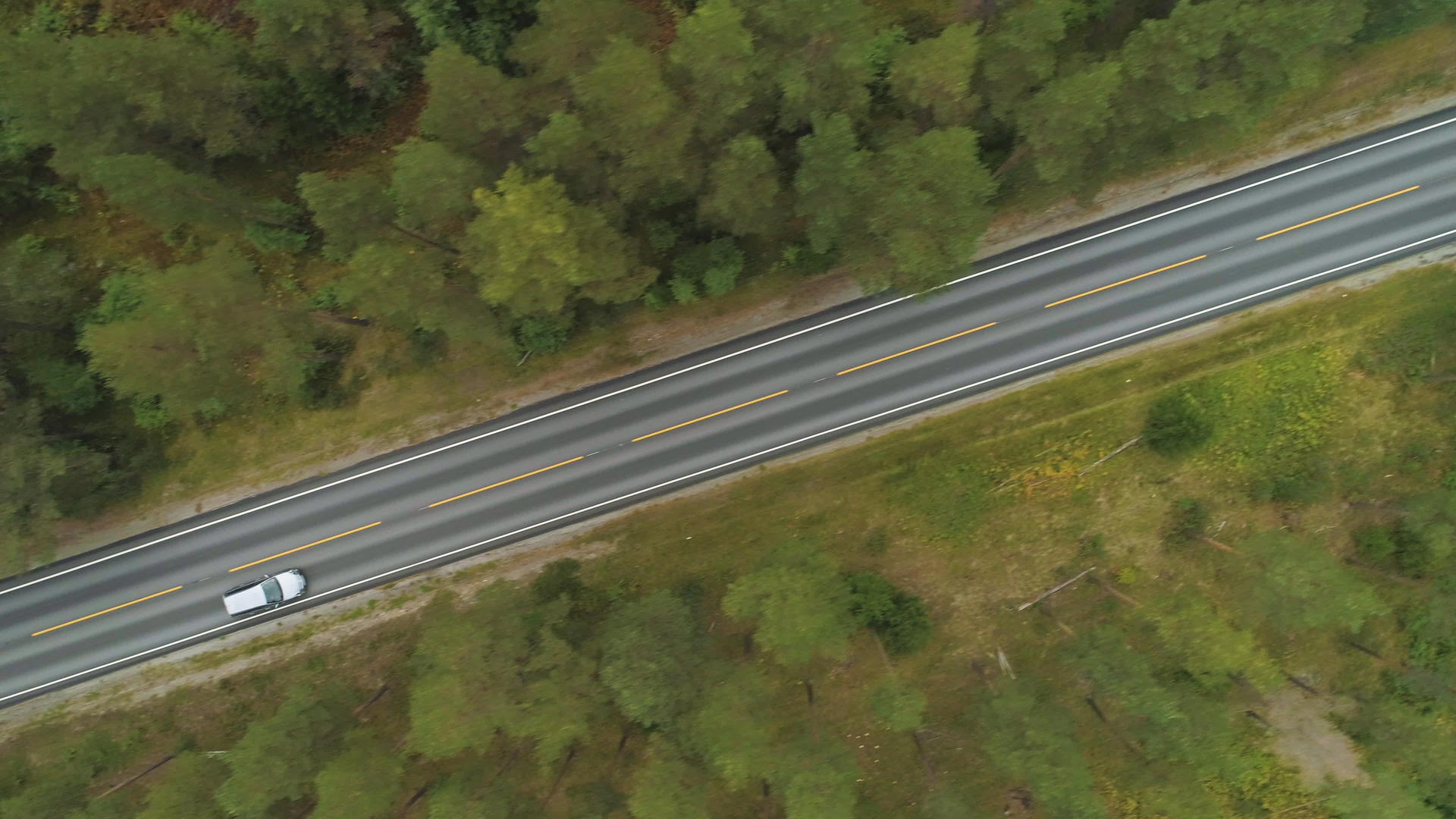 夏天汽车在挪威绿色森林的笔直道路上垂直俯视无人机视频的预览图