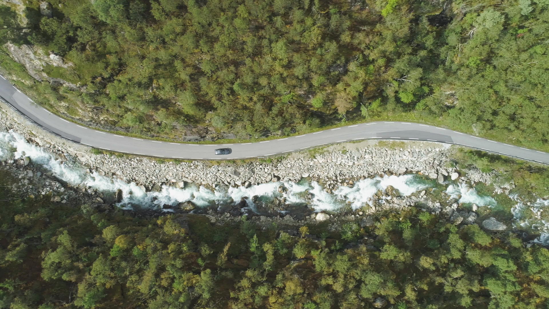 夏天汽车在挪威山沟的乡间小路上行驶河流和绿色山坡垂直于空中视频的预览图