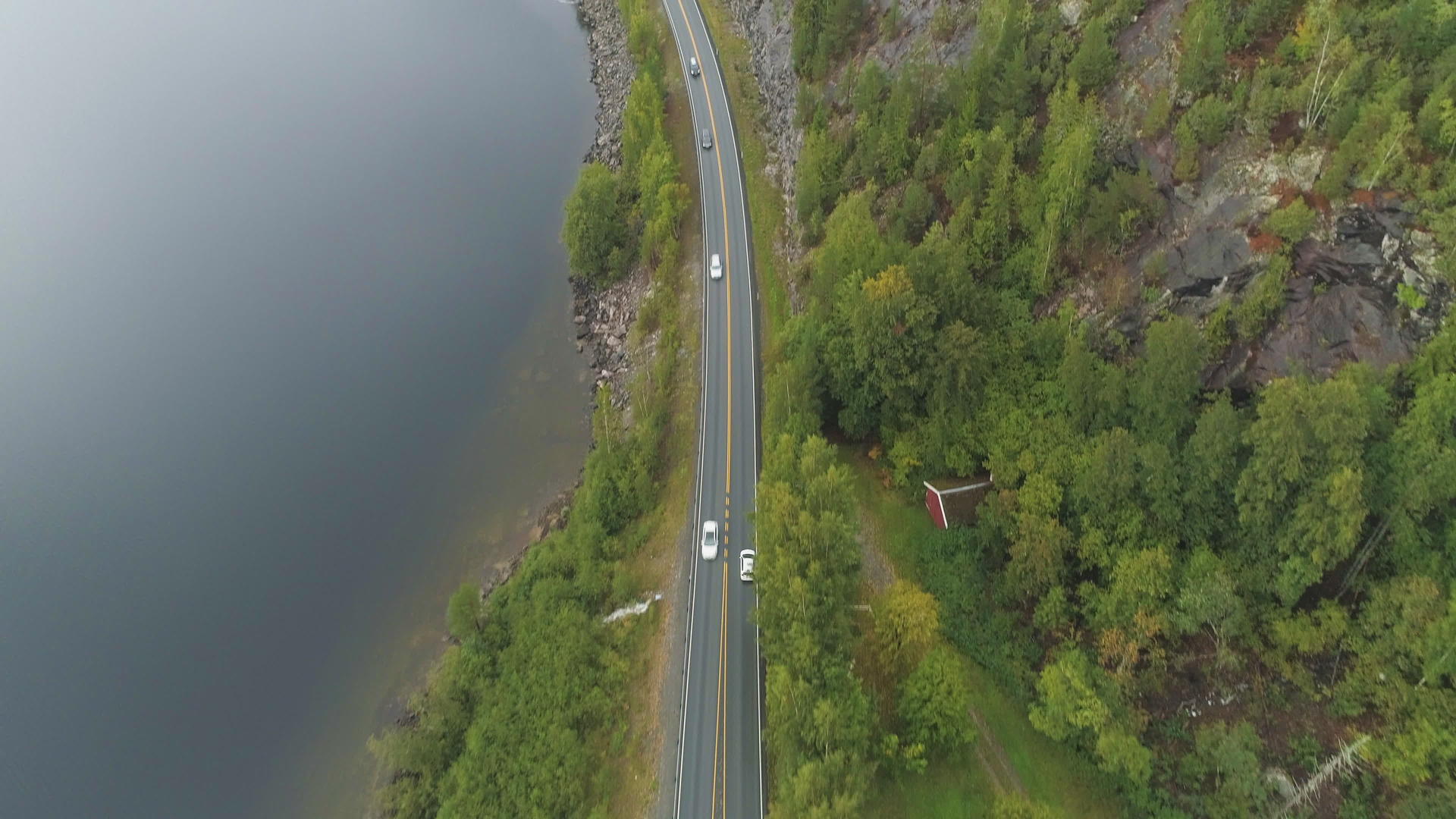 夏天阴天汽车在挪威湖附近的乡村道路上空中行驶视频的预览图