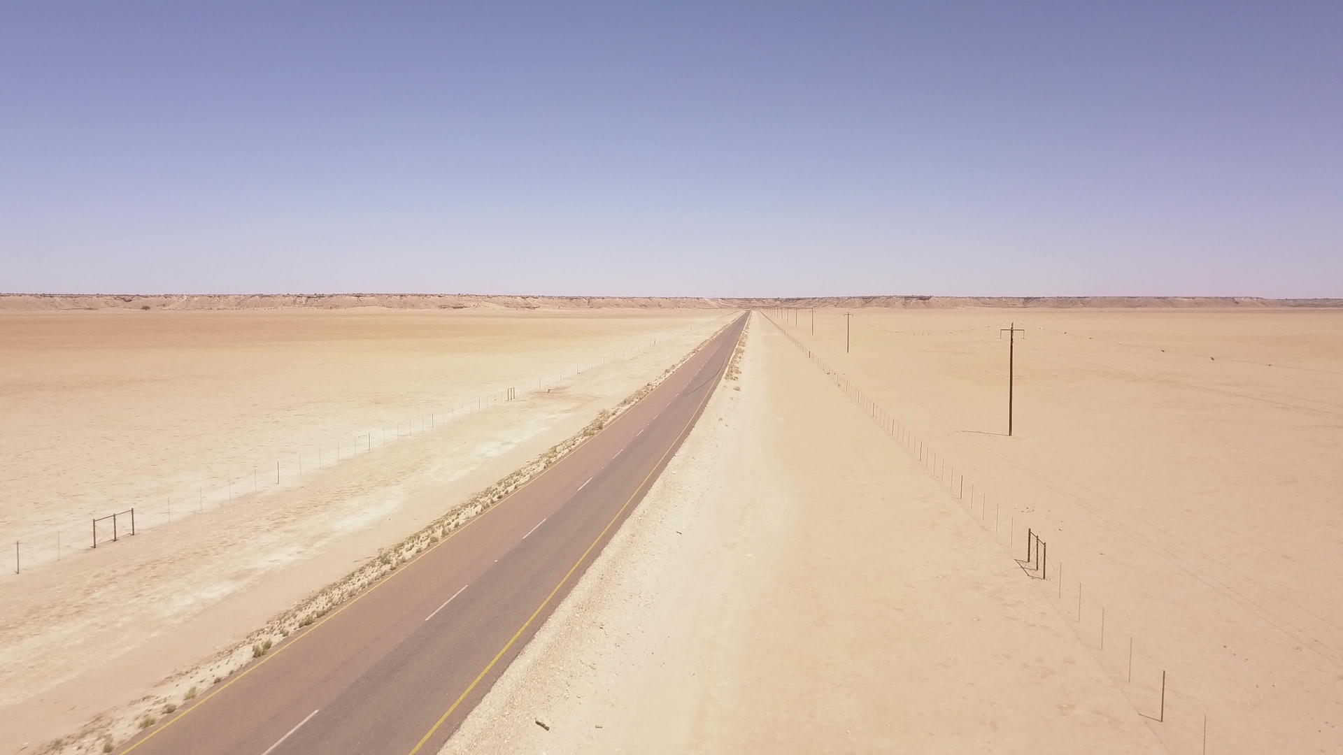 长长的穿越沙漠地貌的道路在空中飞行视频的预览图