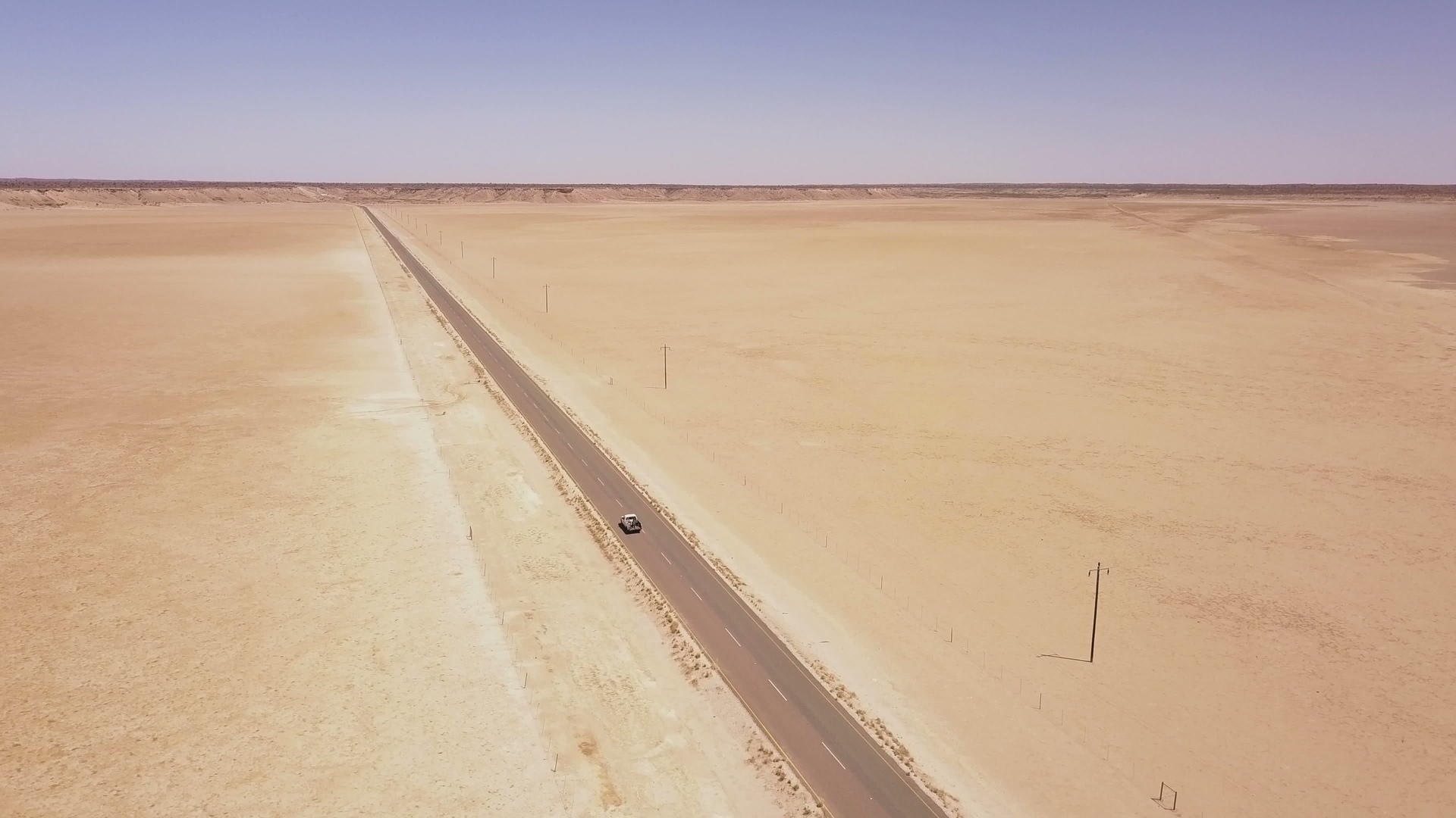 长长的穿越沙漠地貌的道路在空中飞行视频的预览图