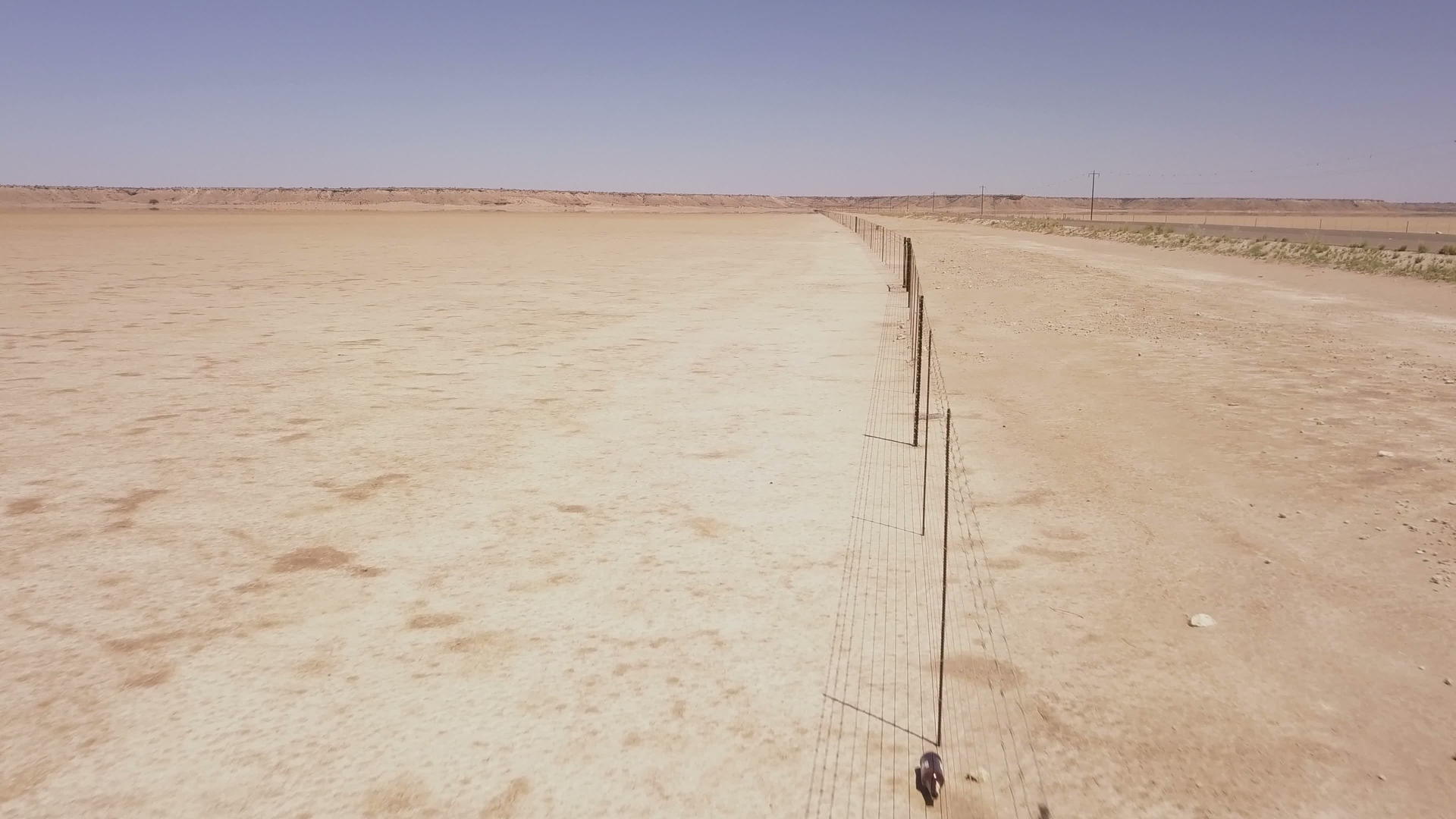 长栅栏穿过沙漠景观在空中飞行视频的预览图